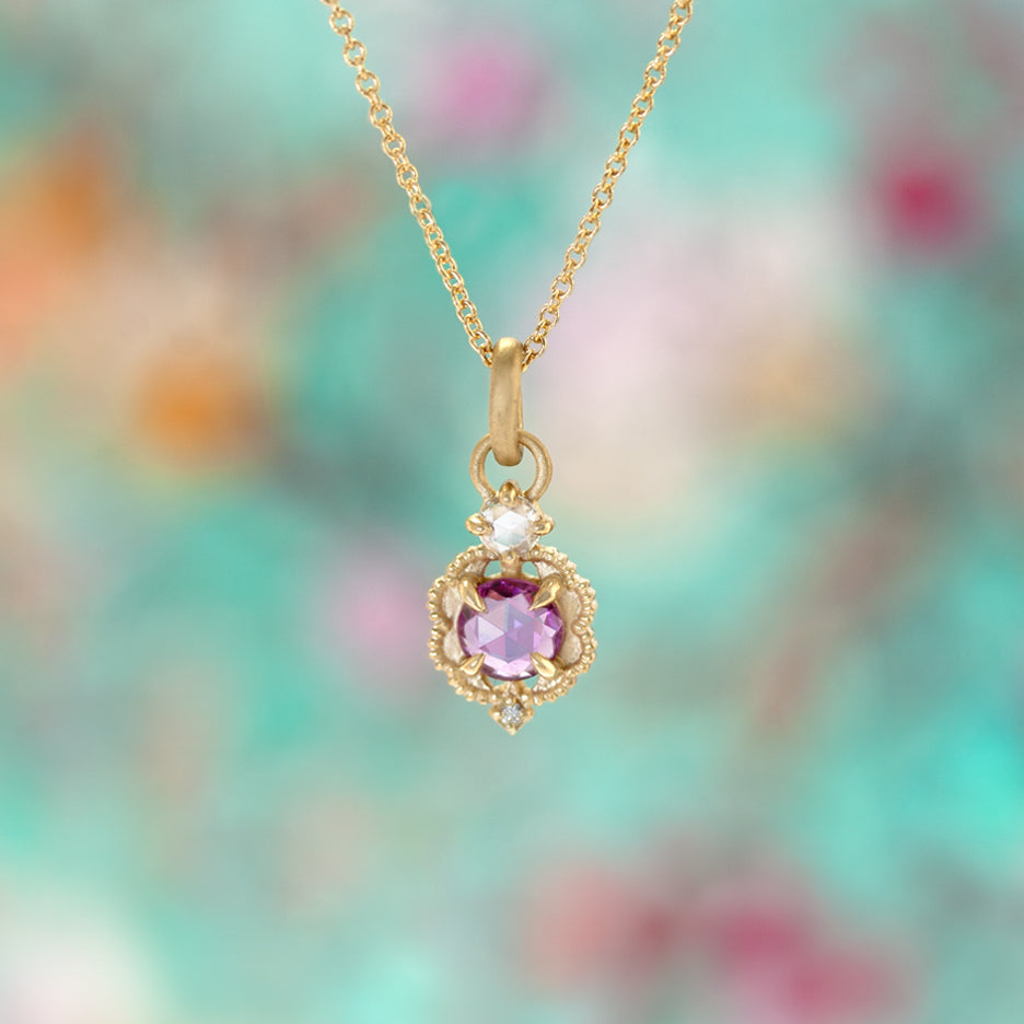 Handmade pendant necklace featuring vintage inspired venise frame setting and rose cut and round brilliant cut diamond accents and pink rose cut sapphire center stone with claw prongs and beading in 18K yellow gold by Designer Megan Thorne