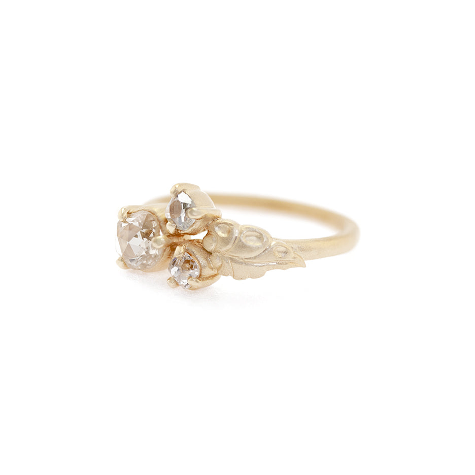 Handmade nontraditional engagement ring featuring 3 rustic antique diamonds and floral leaf details in 18K yellow gold by Designer Megan Thorne