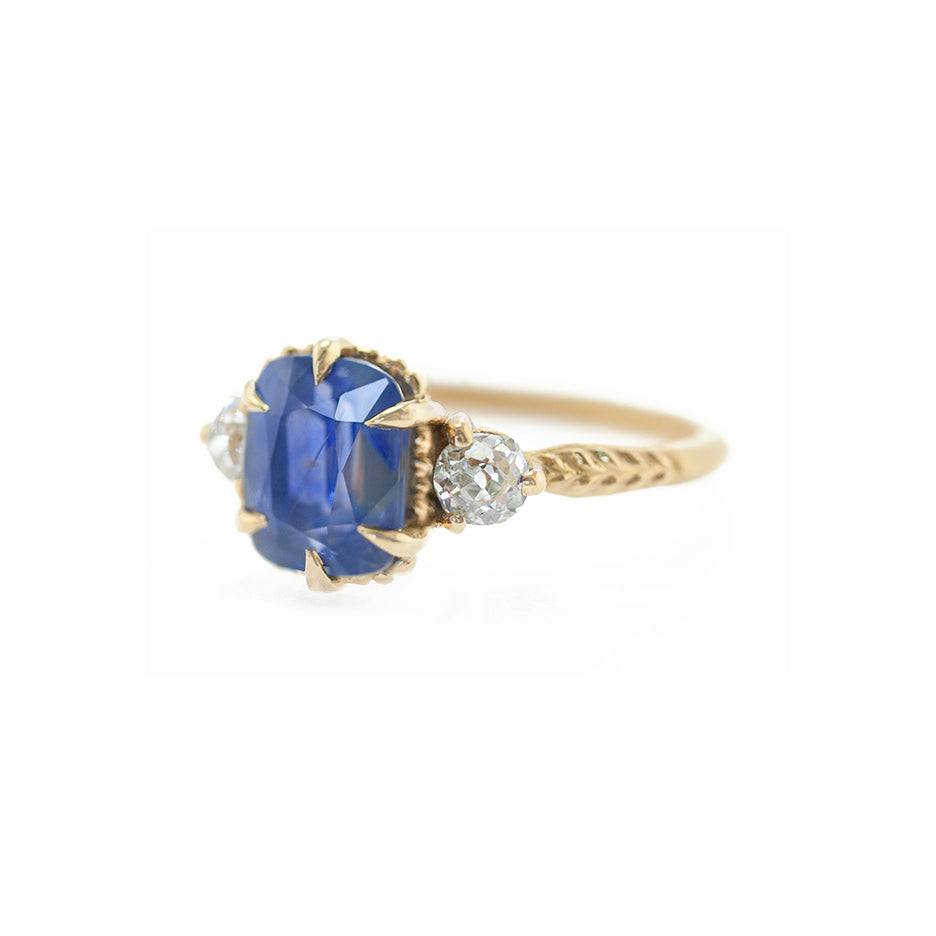 Handmade 3-stone engagement ring with natural blue sapphire and old mine cut diamonds in 18K yellow gold by Designer Megan Thorne