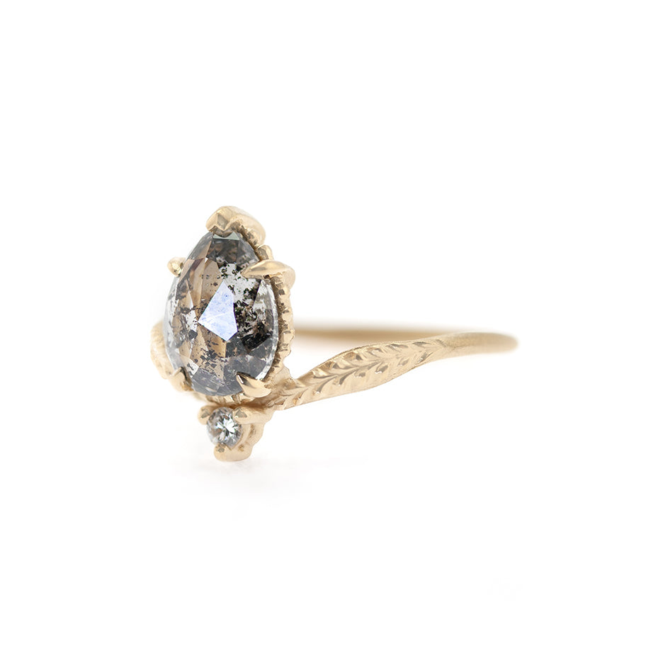Handmade alternative engagement ring featuring 1.46ct pear rose cut salt and pepper diamond with curved shank with botanical Evergreen details in 18K yellow gold by Designer Megan Thorne