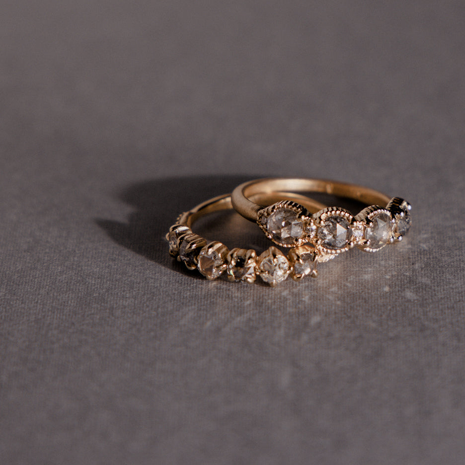 rose cut salt &amp; pepper diamonds and antique white diamonds in vintage inspired Evergreen Mixie wedding band on colored background