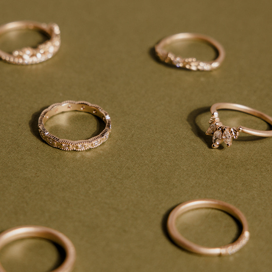 Handmade diamond eternity wedding band or stacking ring with ribbing and beading in 18K yellow gold by Designer Megan Thorne pictured on colored background