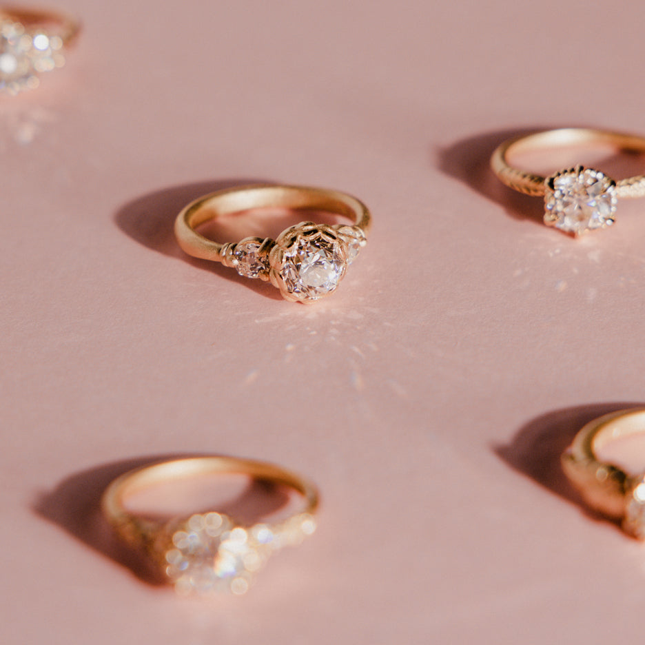 Yellow gold rings with diamond accents on a pink background
