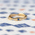 Handmade classic wedding band with scallops to nestle close to engagement ring featuring diamonds and blue sapphires with ribbing in 18K yellow gold by Designer Megan Thorne