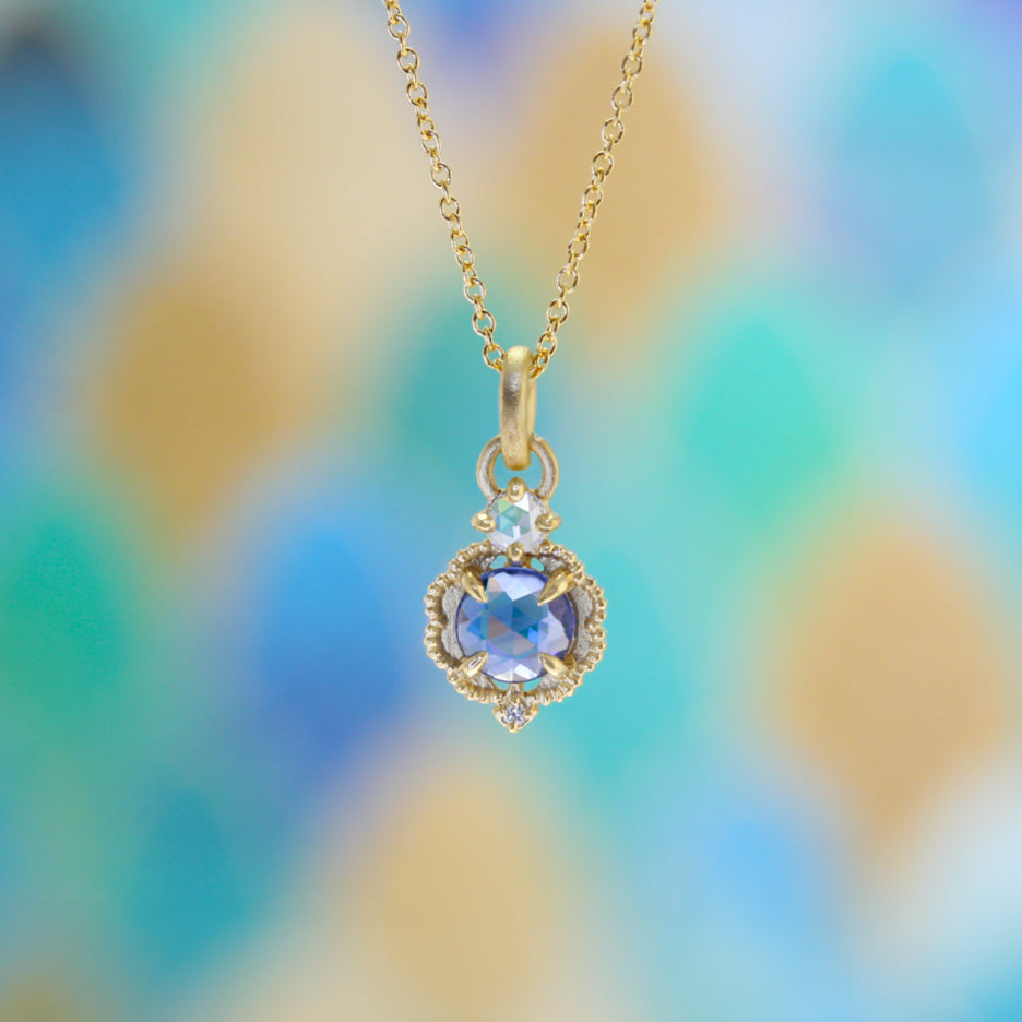 Handmade pendant necklace featuring vintage inspired venise frame setting and rose cut and round brilliant cut diamond accents and blue rose cut sapphire center stone with claw prongs and beading in 18K yellow gold by Designer Megan Thorne