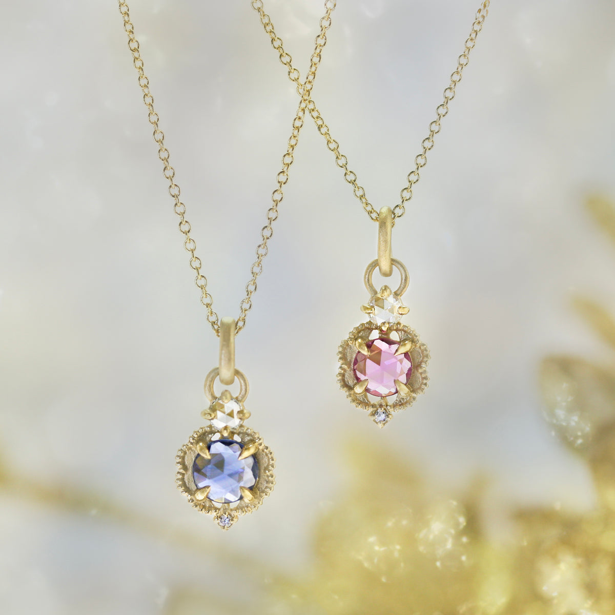 Handmade pendant necklace featuring vintage inspired venise frame setting and rose cut and round brilliant cut diamond accents and blue rose cut sapphire center stone with claw prongs and beading in 18K yellow gold by Designer Megan Thorne on colored background with blue sapphire version