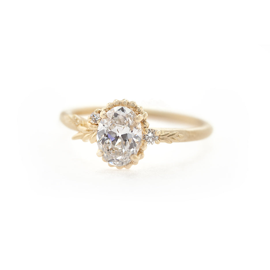 Handmade engagement ring with oval lab grown vintage cut diamond and floral details in 18K yellow gold by Designer Megan Thorne