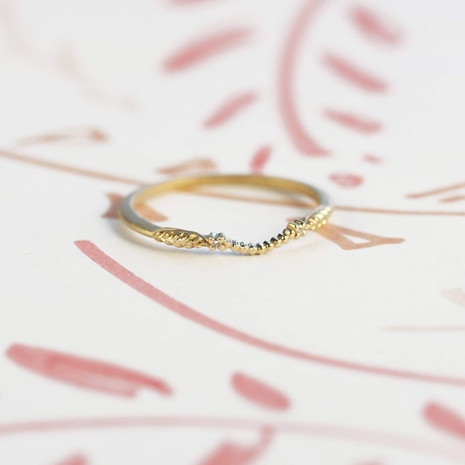 Handmade wedding band curved to guard engagement ring with botanical inspired Evergreen details and diamonds in 18K yellow gold by Designer Megan Thorne