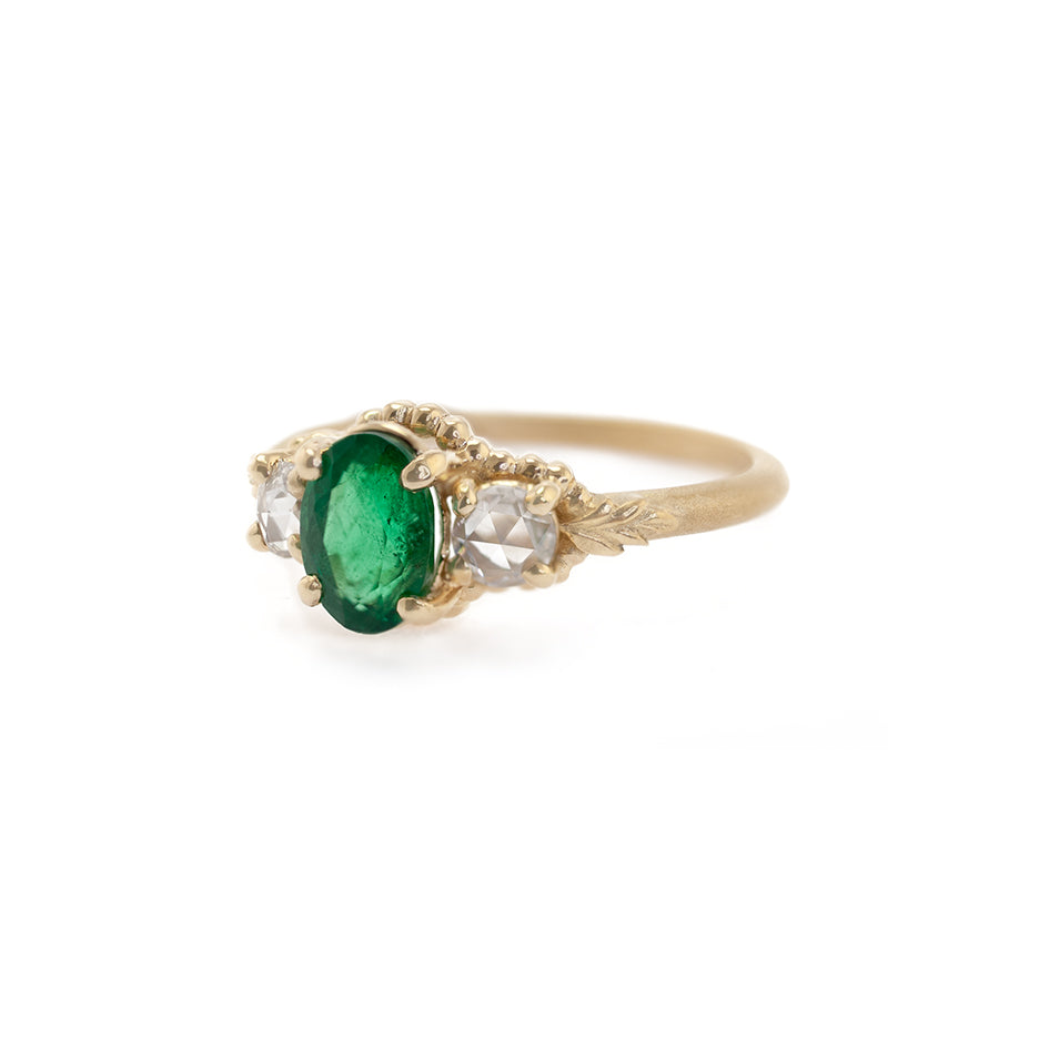 Handmade alternative 3-stone engagement ring with an oval emerald and rose cut side diamonds and floral Wood Nymph details in 18K yellow gold by Designer Megan Thorne