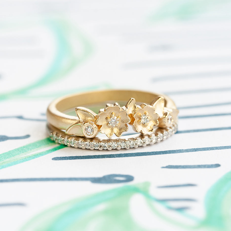 Handmade pave wedding or stacking band with diamonds and beading in 18K white gold thin version by Designer Megan Thorne pictured with other stacking band on colored background