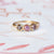 Handmade wedding or stacking band with red pink purple orange tonal blend sapphires and brilliant cut accents with ribbed details in 18K yellow gold by Designer Megan Thorne