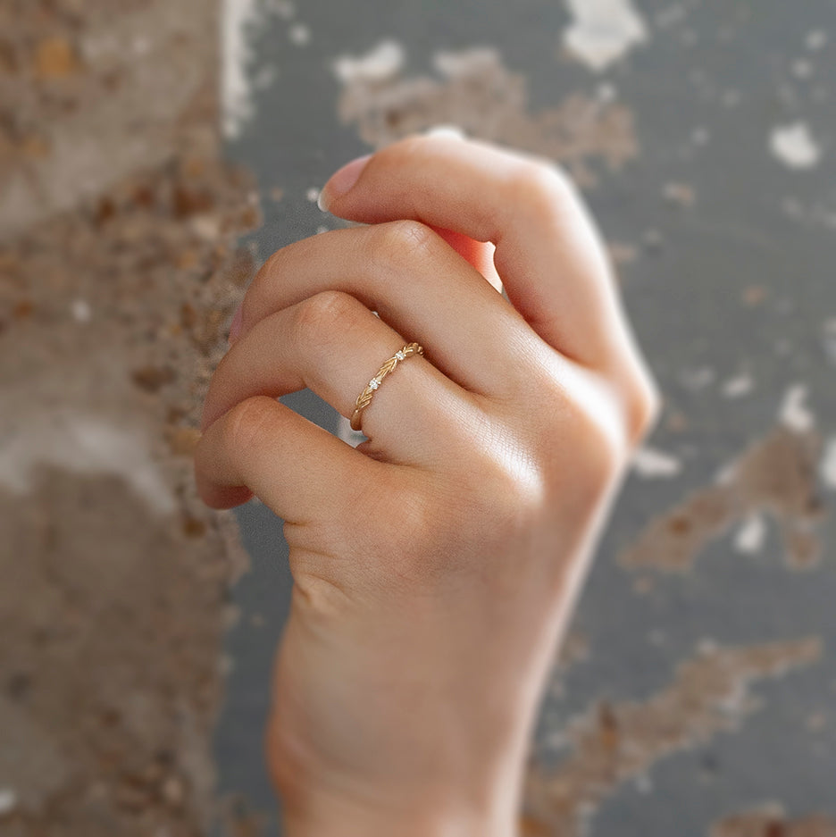 Handmade wedding band with floral details in the top third and diamond accent stones by Designer Megan Thorne on hand