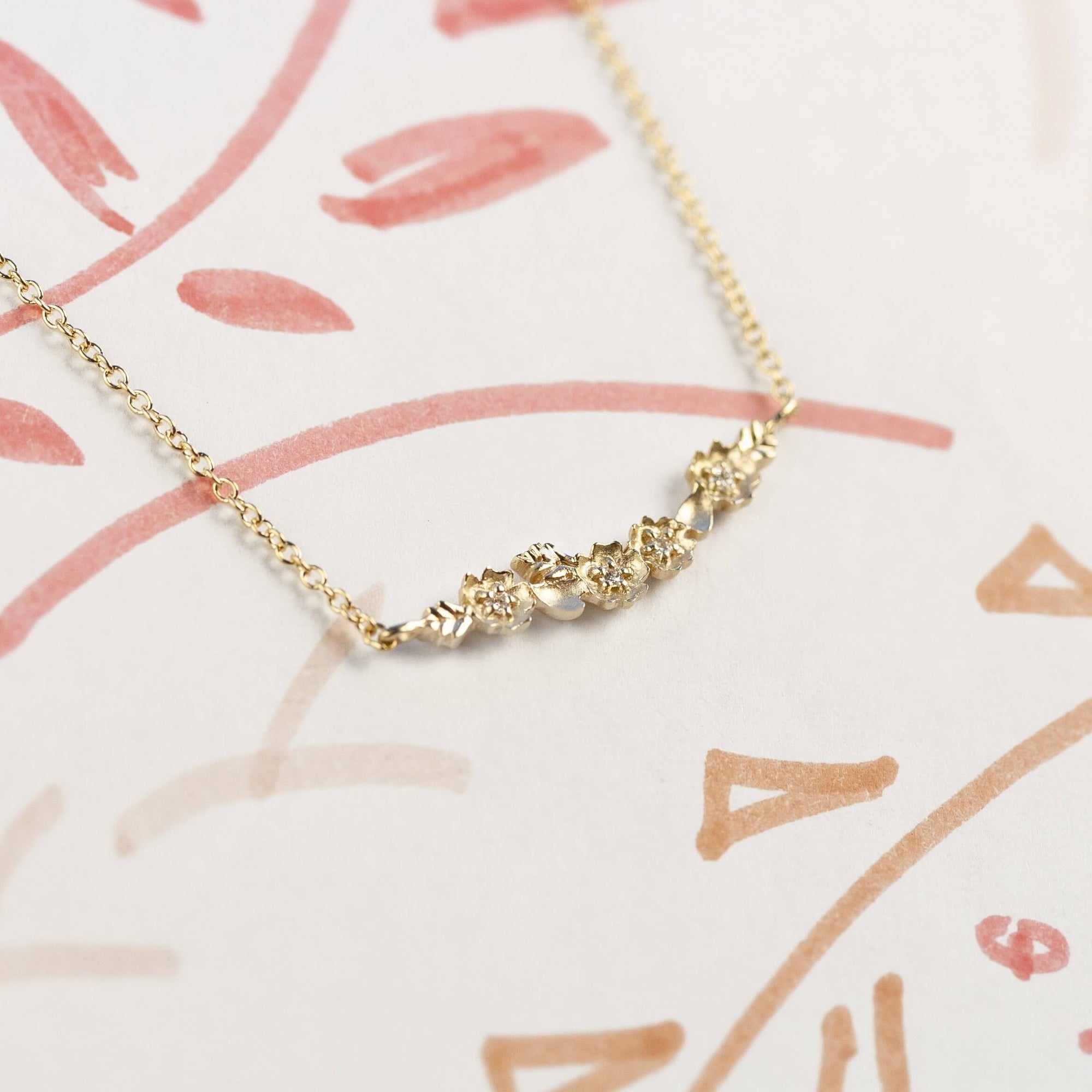 Handmade everyday bar necklace with floral Buttercup stations and botanical leaves in 18K yellow gold by Designer Megan Thorne