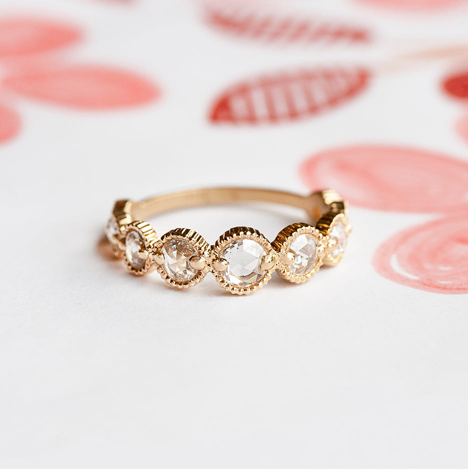 Handmade graduated wedding band with rose cut diamonds and ribbed details in 18K yellow gold by Designer Megan Thorne on colored background