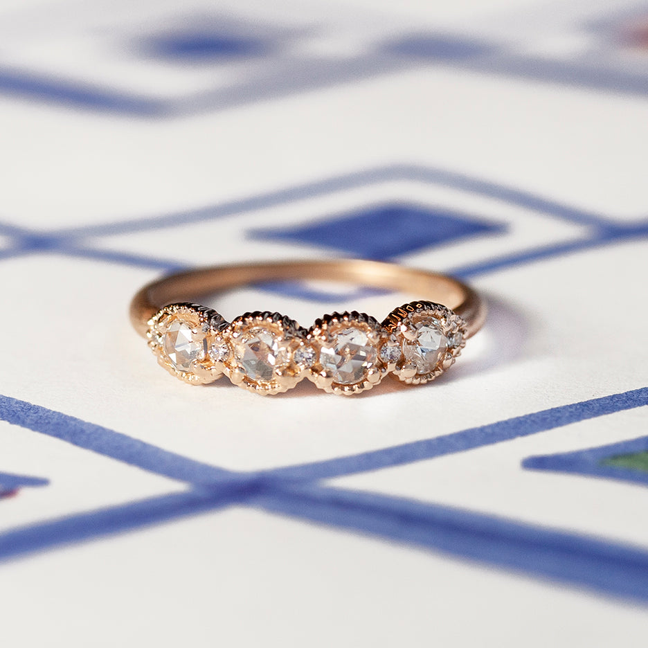 Handmade wedding or stacking band with rose cut diamonds and brilliant cut accents with ribbed details in 18K rose gold by Designer Megan Thorne on colored background